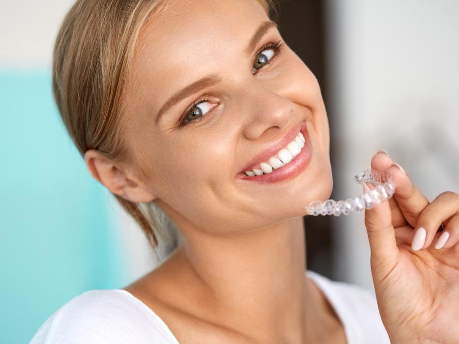 Woman smiling with aligner in hand, scottsdale az