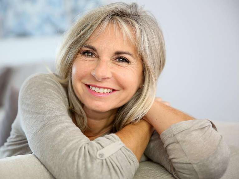 Older woman with gray hair smiling on a couch, scottsdale az