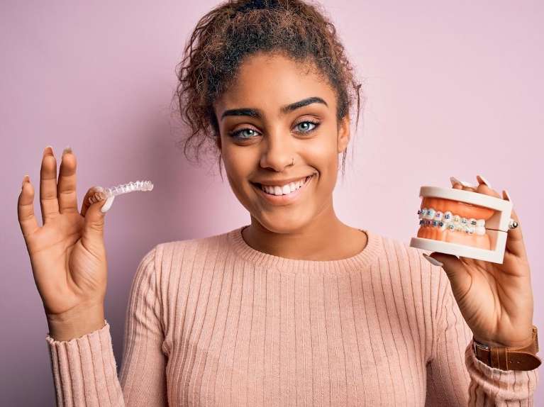 Girl holding clear aligner and mold of teeth with braces, scottsdale az